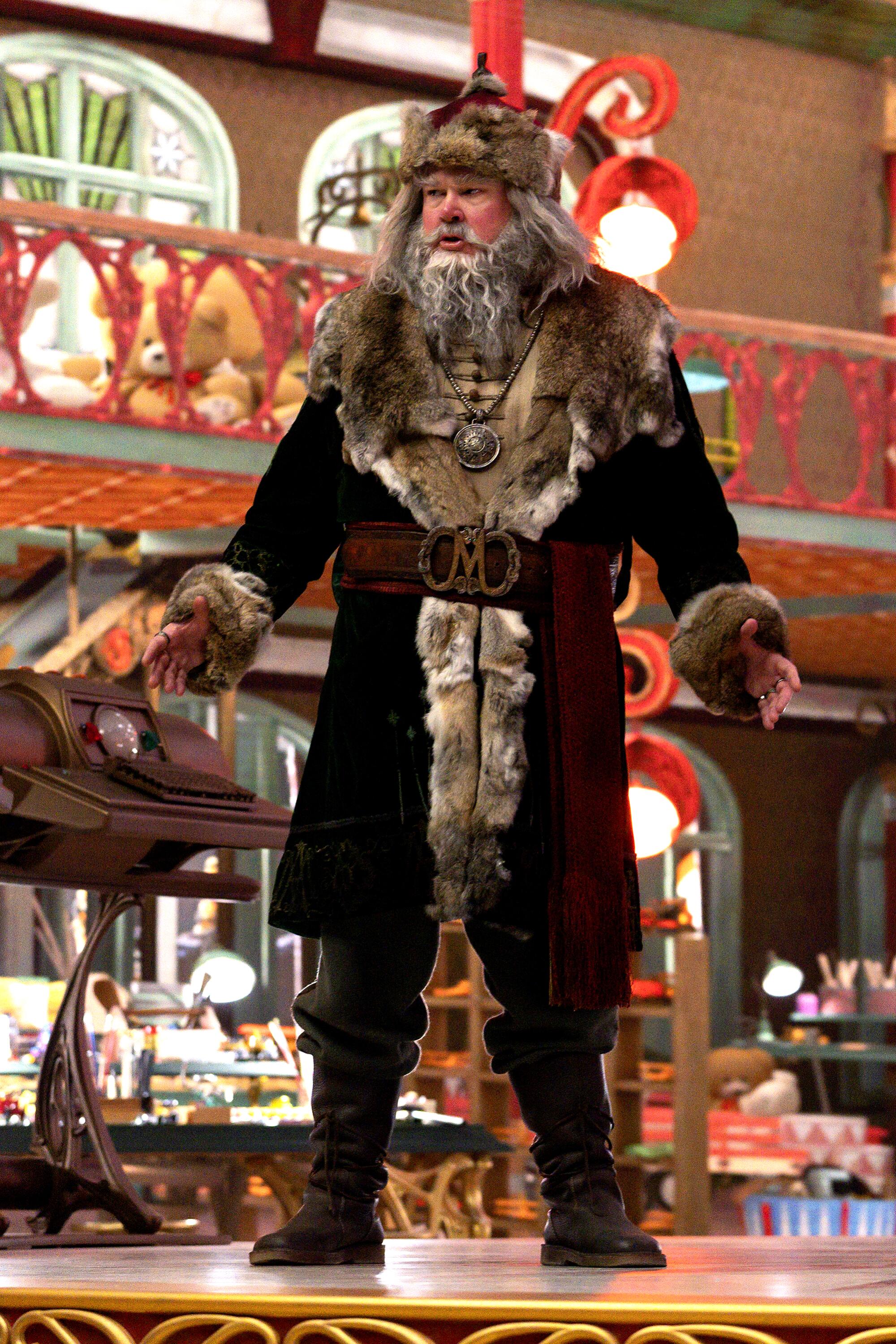 A man dressed as Santa in a red coat and hat trimmed with brown fur.