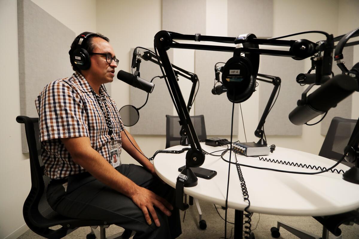 A man sits in front of a microphone in a recording studio