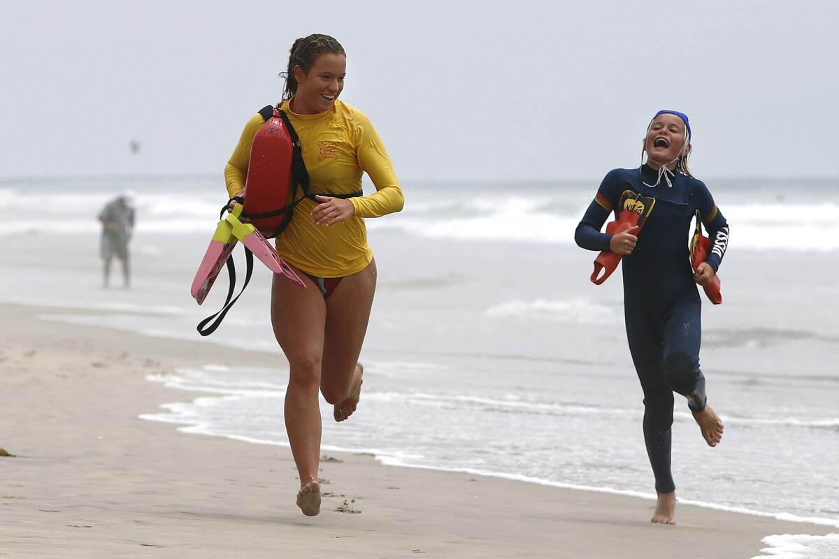 California State Beach lifeguard Montana White, 19, left, races junior lifeguard Kai Shelley, 13, right, to the finish line.