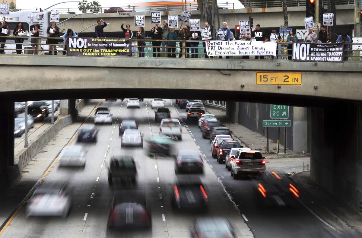 Protesters from the Refuse Fascism group on a bridge over the busy 101 Freeway