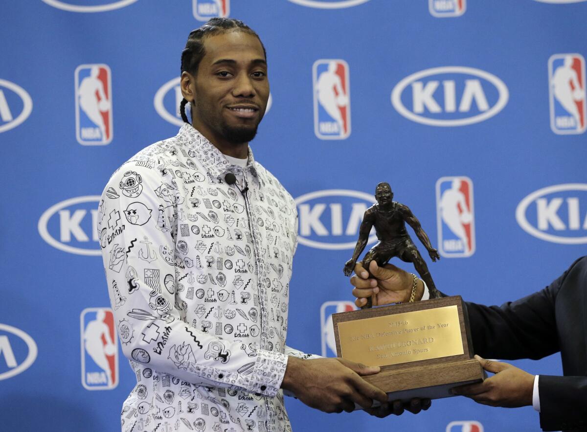 Spurs forward Kawhi Leonard poses with his trophy during a news conference where he was named the NBA defensive player of the year.