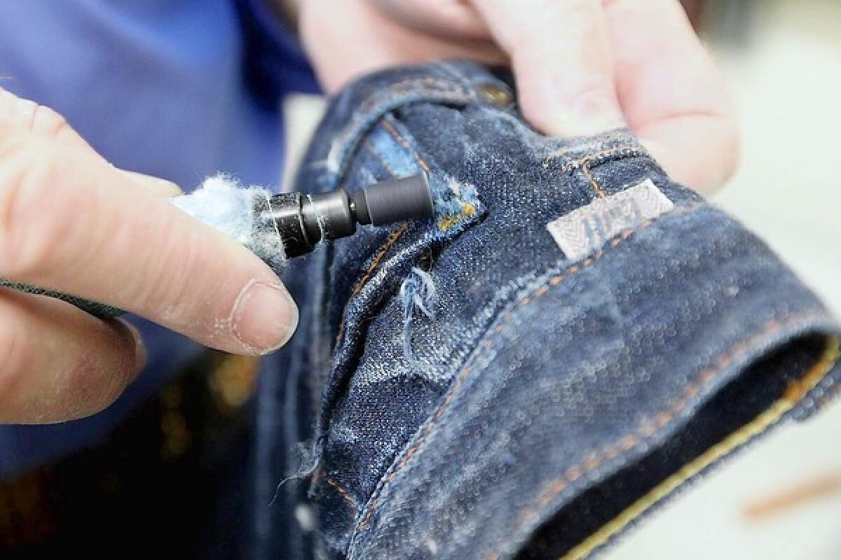 A pair of jeans is sanded to help give an "aged" look to denim at a Gardena laundry facility.