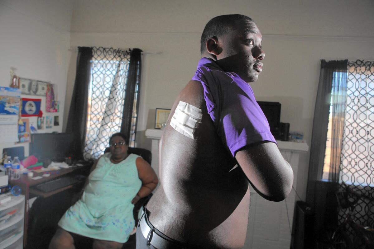 Jamar Nicholson, 15, shows the bandage covering the wound in his back where he was shot by Los Angeles police as his mother, Geraldine Nicholson, looks on.
