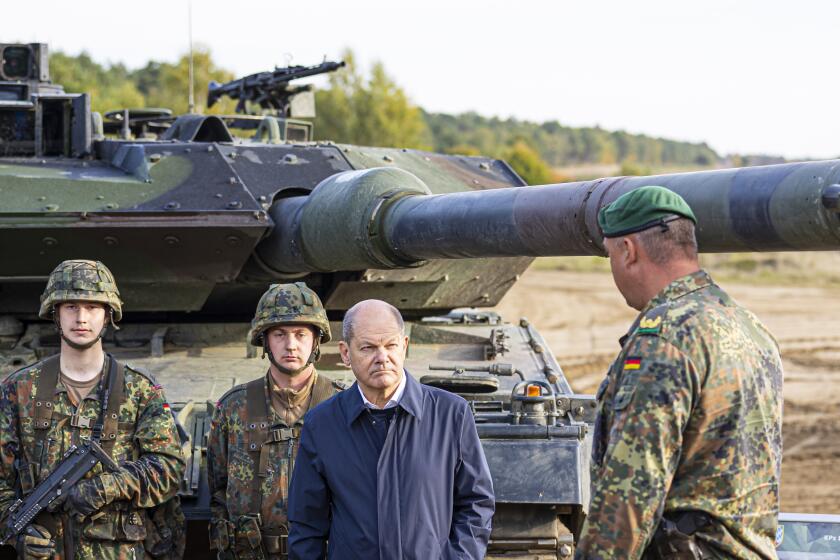 FILE - German Chancellor Olaf Scholz stands with German army Bundeswehr soldiers at a "Leopard 2" main battle tank during a training and instruction exercise in in Ostenholz, Germany, Monday, Oct. 17, 2022. Scholz is expected to announce Wednesday, Jan. 25, 2023 that his government will approve supplying German-made battle tanks to Ukraine. (Moritz Frankenberg/dpa via AP, File)