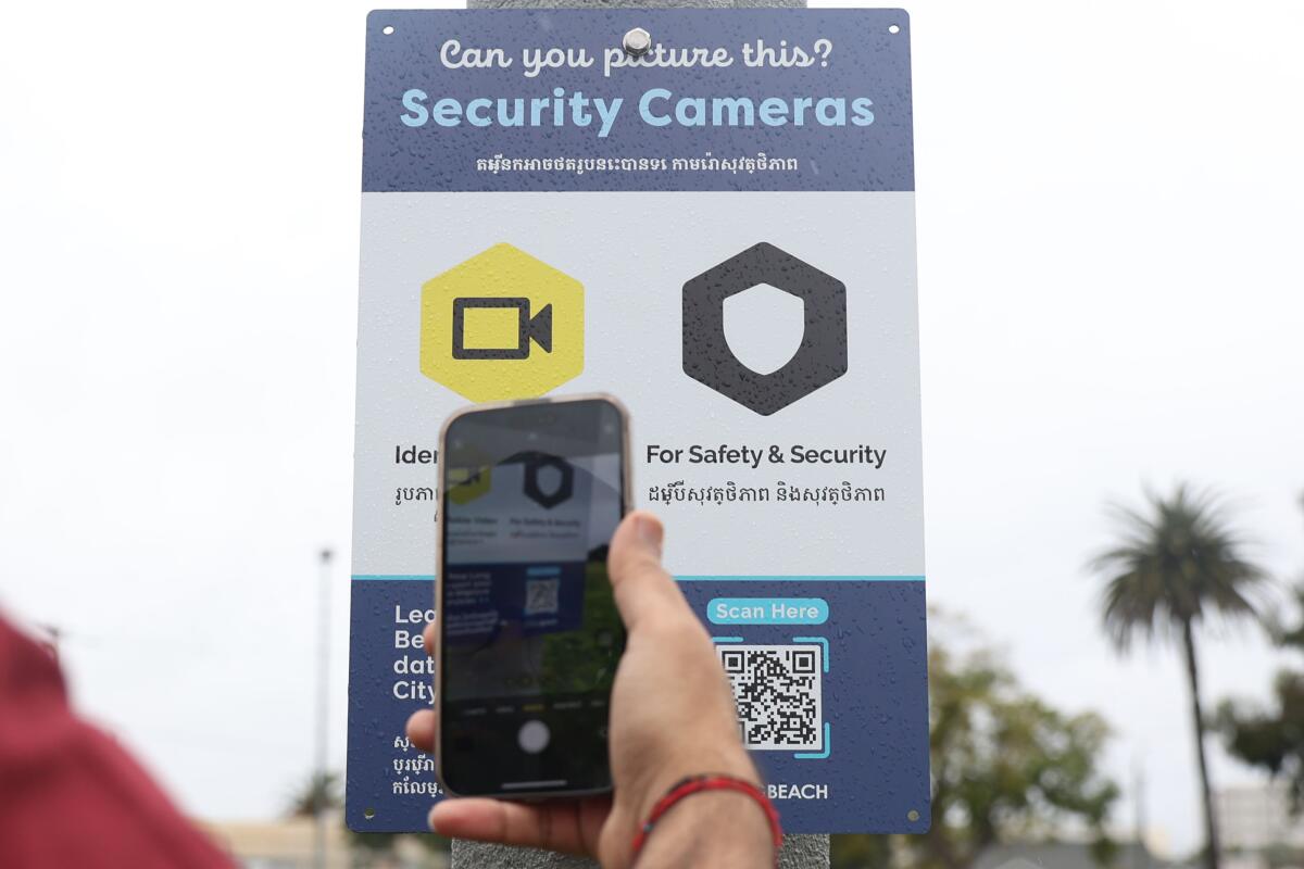 A person scans a QR code to find out what data Long Beach's security cameras log about residents near a library.