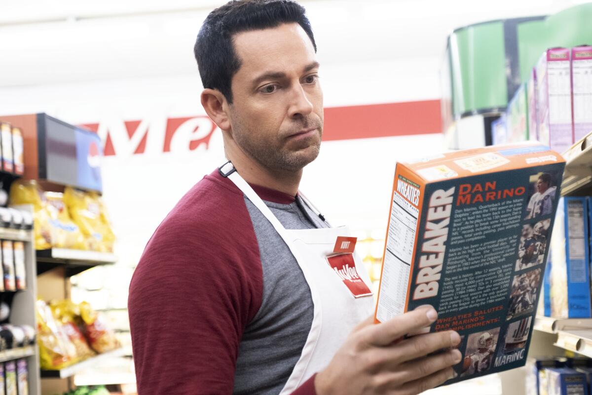 A man wearing a white apron stares at a Wheaties box in a store.