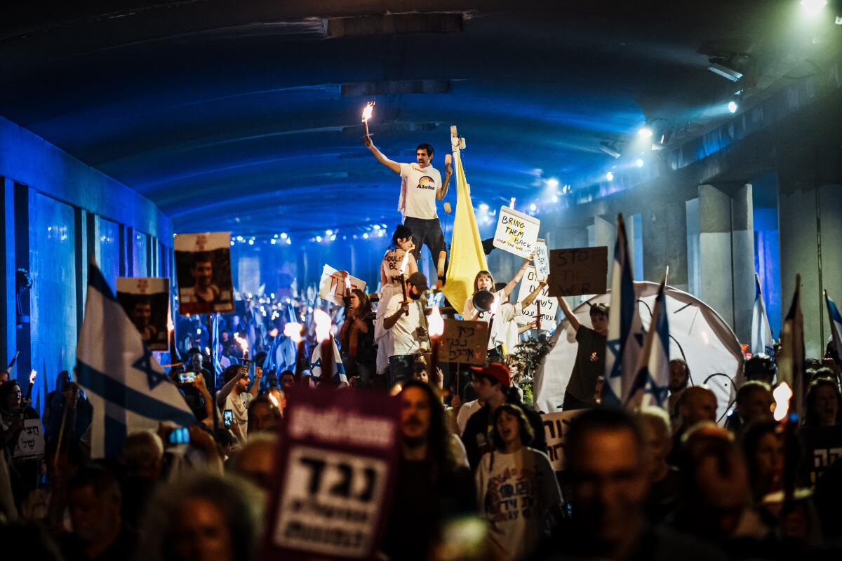 People holding flags, banners and lit candles march through central Jerusalem.