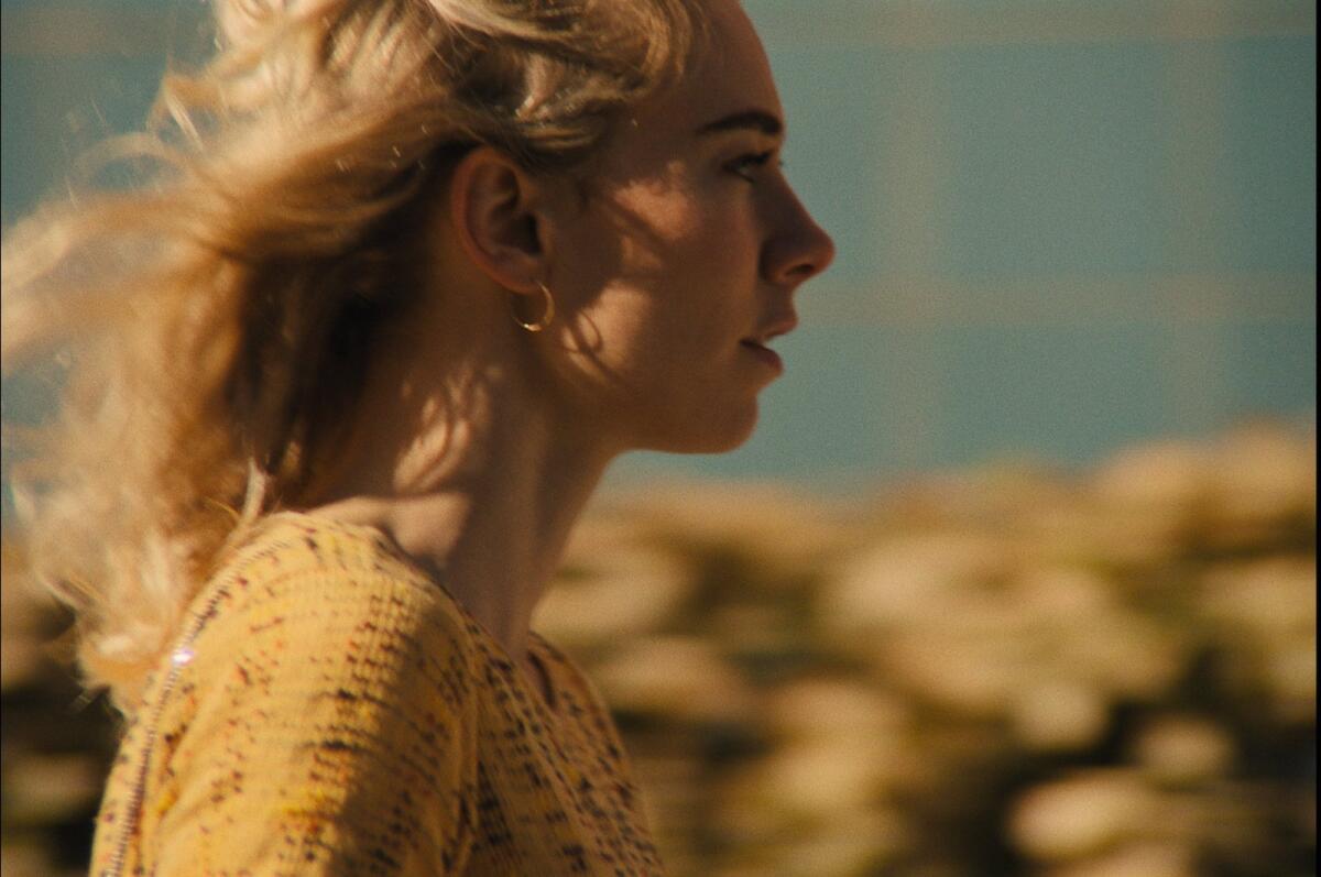 A young blond woman is seen in profile with her hair blowing behind her.