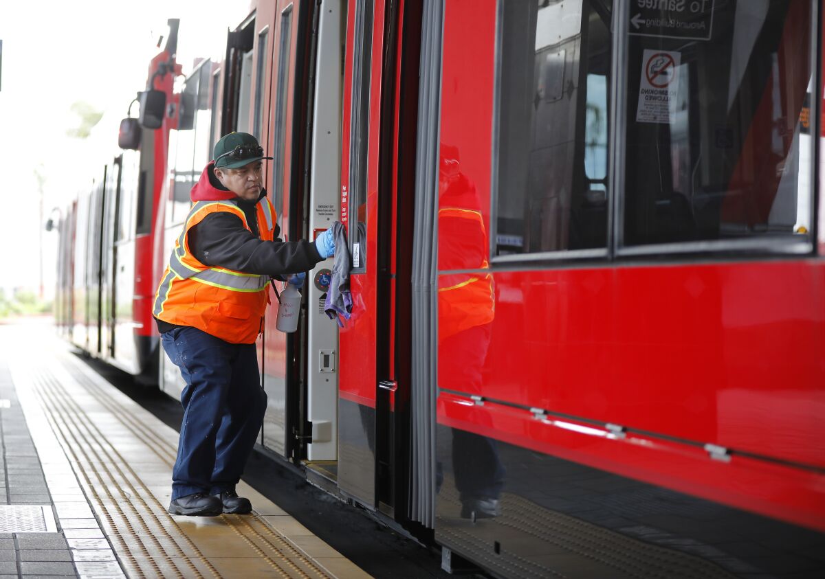 Luis Valenzuela wipes down the door on an MTS trolley in March 2020. 