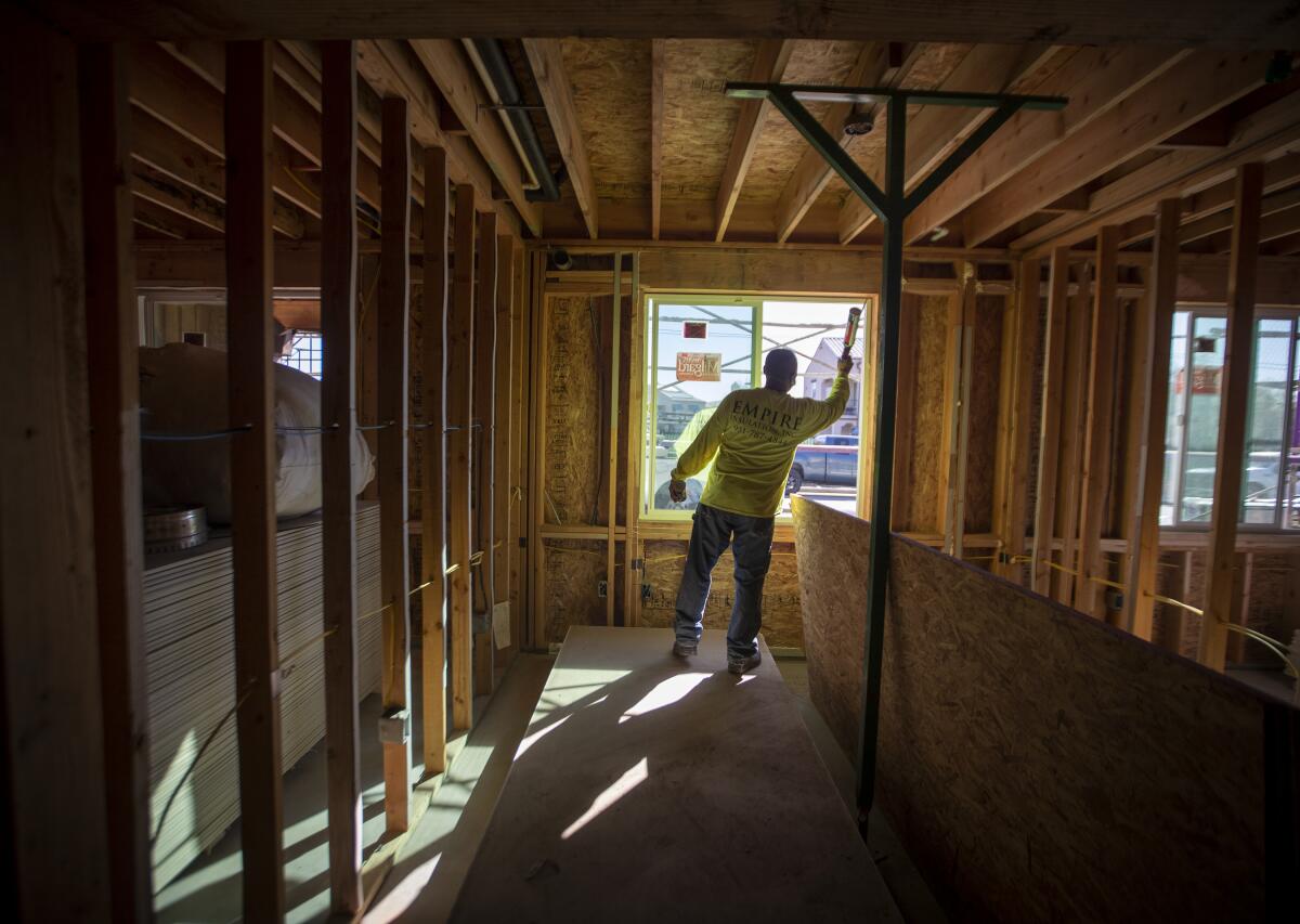 A construction worker seals windows and cracks at an all-electric housing development being built in San Bernardino, Calif.