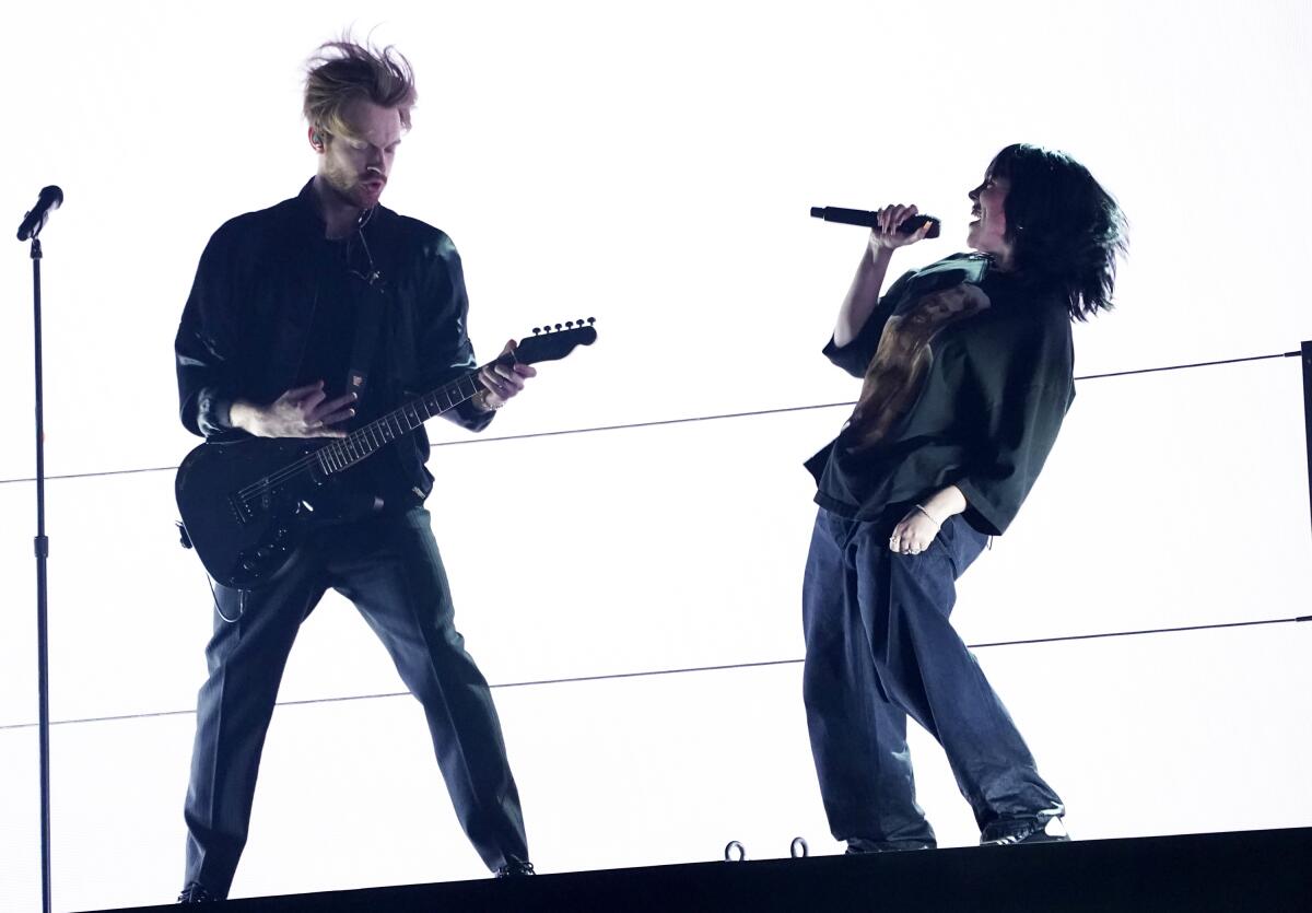 Billie Eilish, right, and Finneas perform "Happier Than Ever" at the 64th Grammy Awards.
