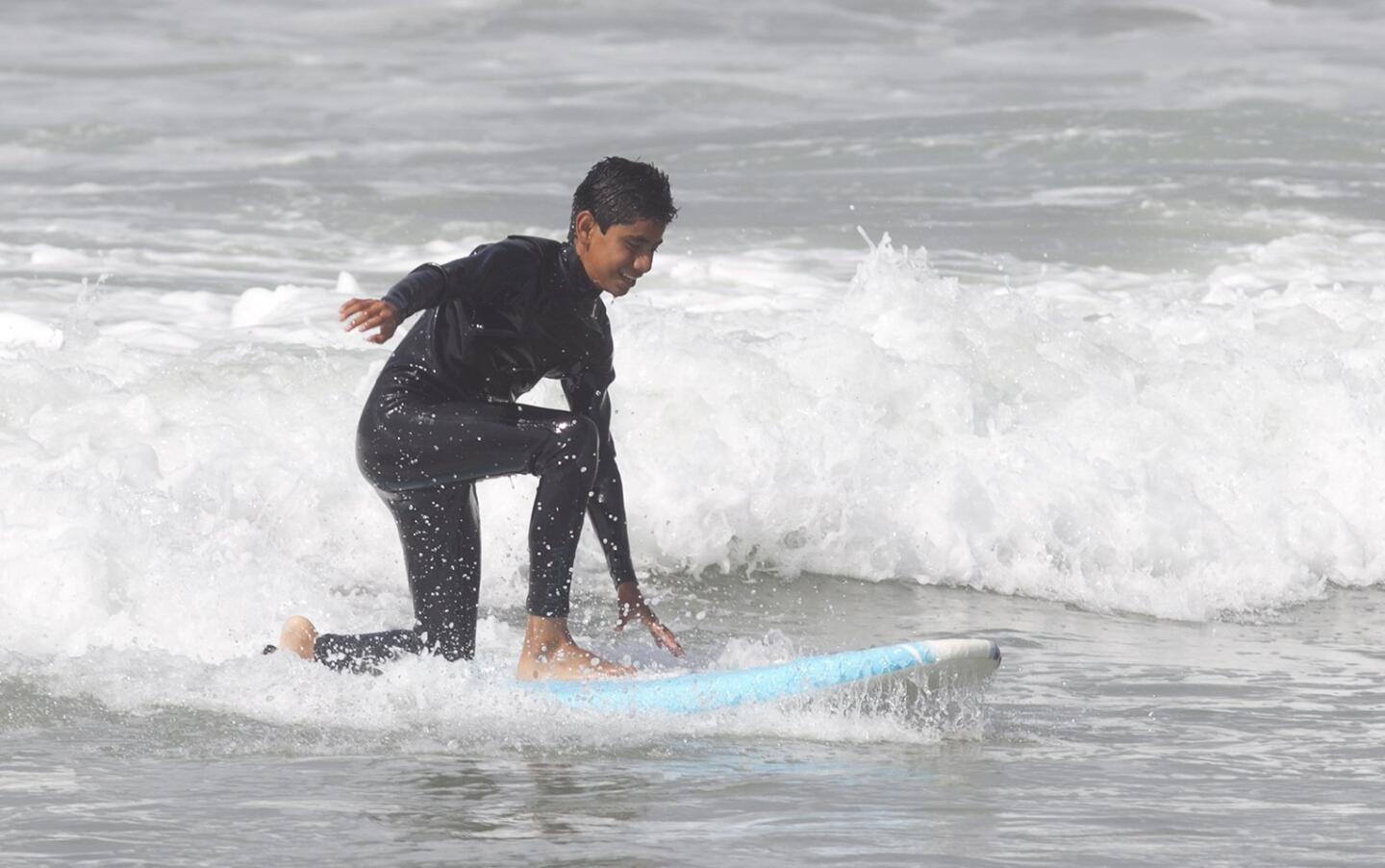 A participant of the Save Our Youth’s Surf Days program gets to his feet in west Newport on Thursday.