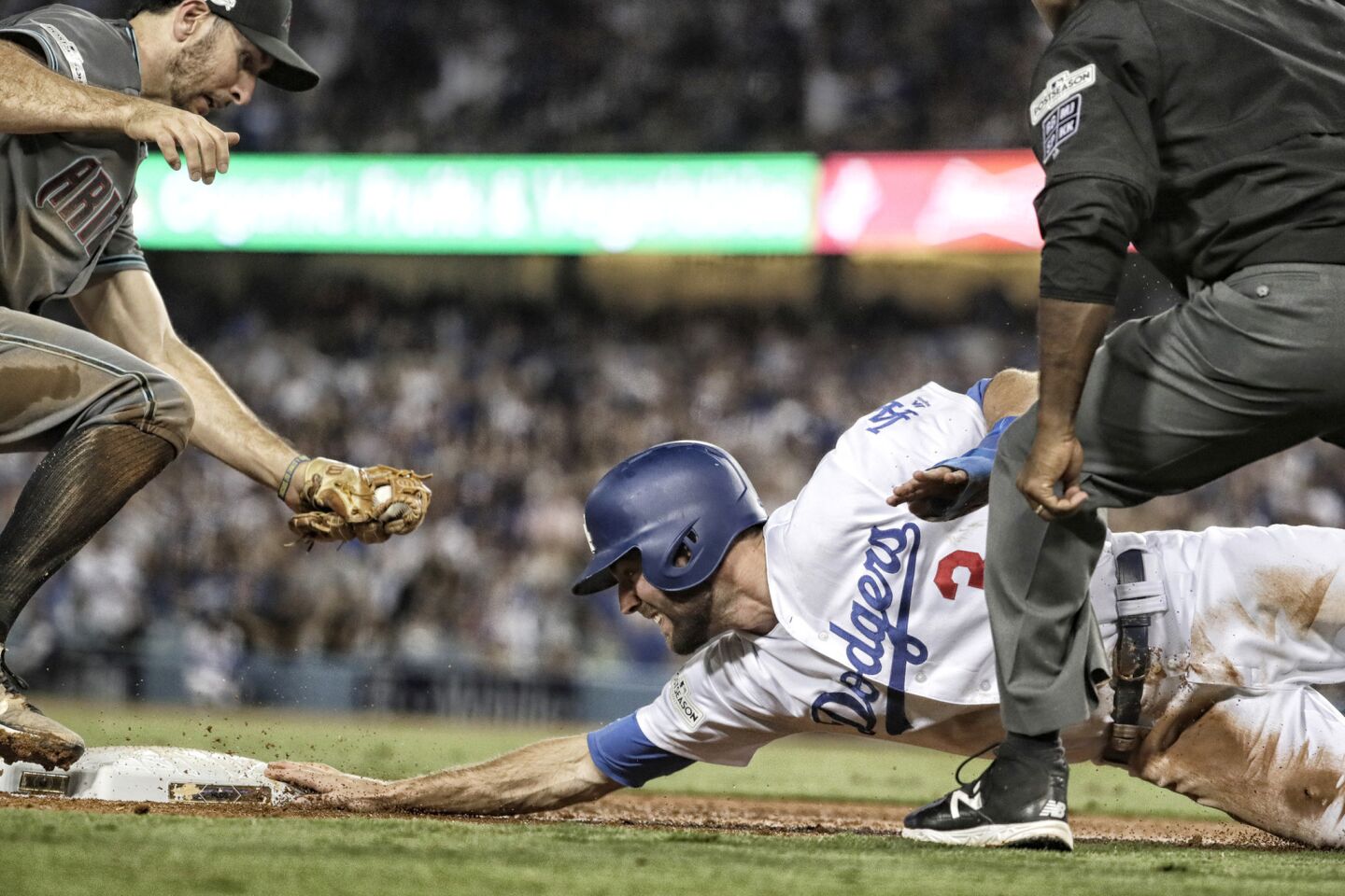 Chris Taylor dives back safely to third base as Diamondback Adam Rosales comes late with the tag during a three-run fourth inning for the Dodgers in Game 1 of the NLDS.