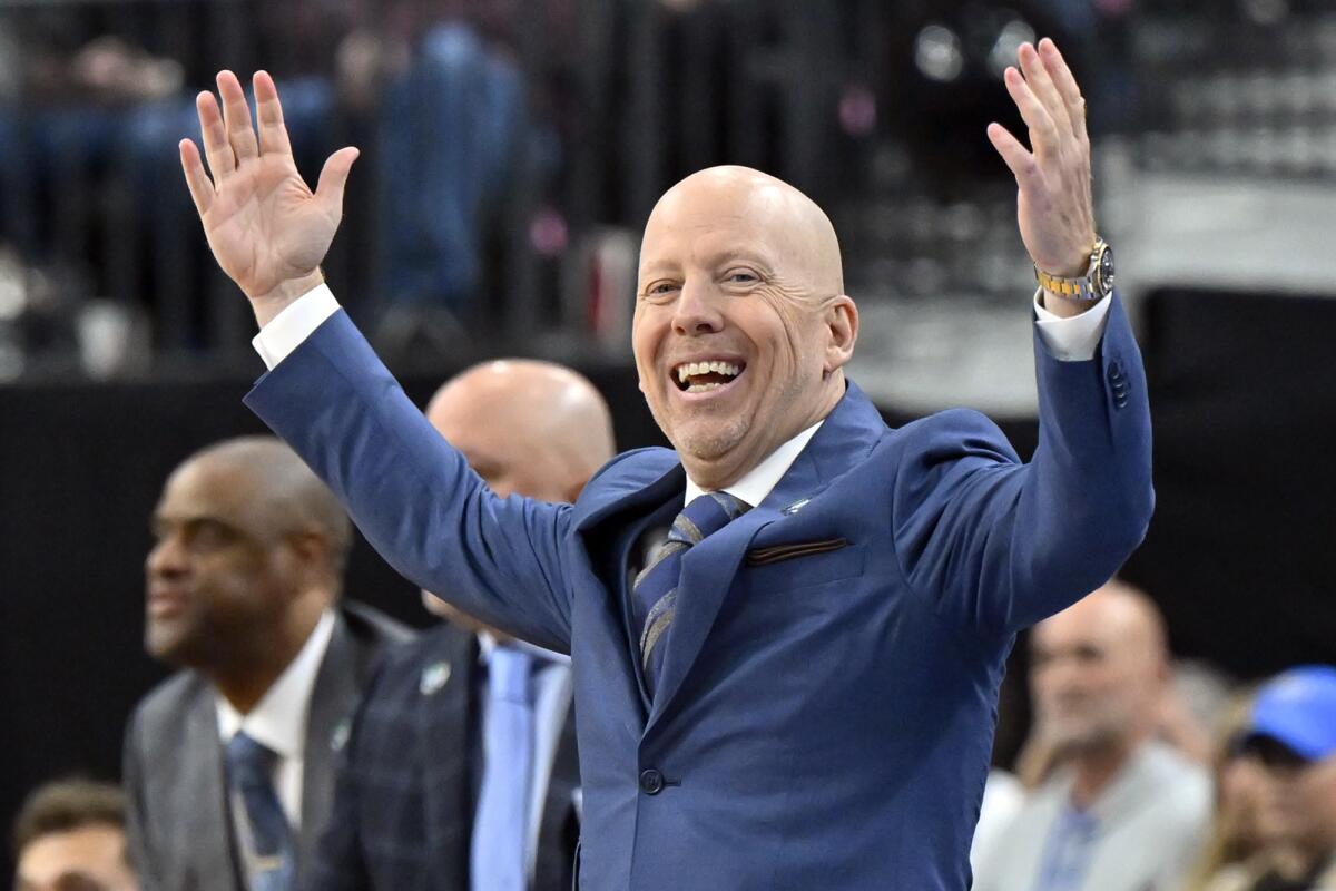 UCLA coach Mick Cronin raises his arms and laughs while watching a play from the sideline.