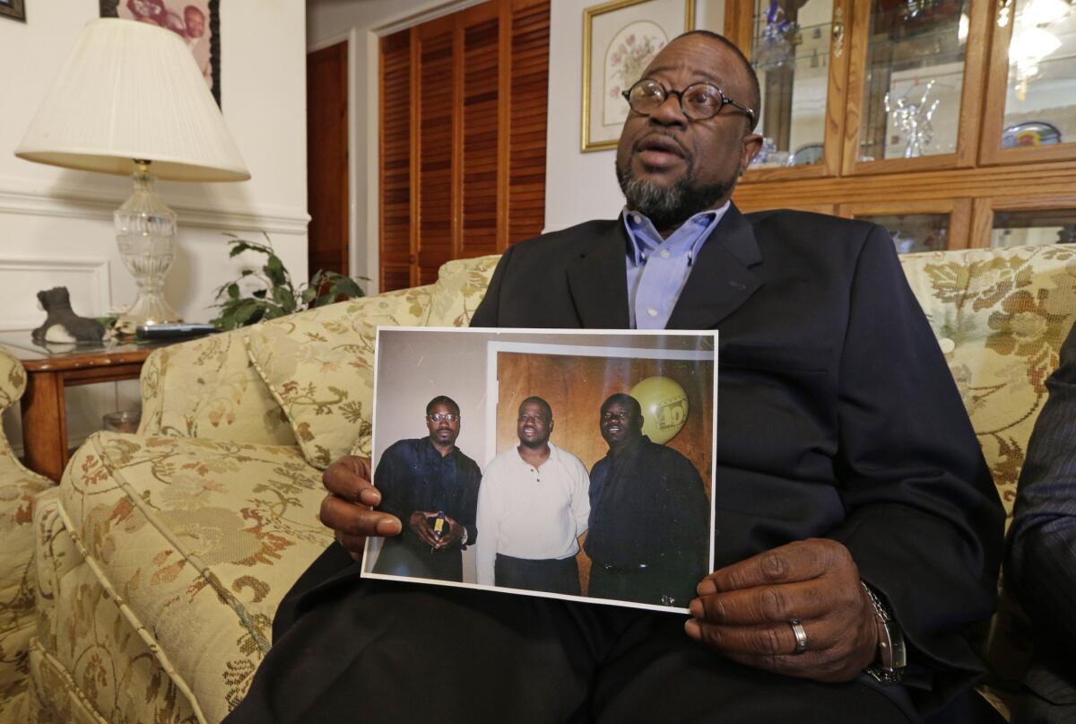 Anthony Scott holds a photo of himself, center, and his brothers Walter Scott, left, and Rodney Scott, right, as he talks about his brother at his home near North Charleston, S.C.