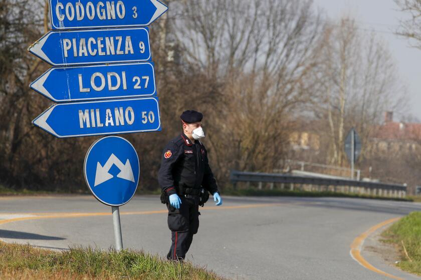 A Carabinieri (Italian paramilitary police) officer checks transit to or from the cordoned area in Codogno, some 50 kilometers South-East of Milan, Italy, Monday, Feb. 24, 2020. Police manned checkpoints around quarantined towns in Italy's north on Monday and residents stocked up on food as the country became the focal point of the outbreak in Europe and fears of its cross-border spread. (AP Photo/Antonio Calanni)