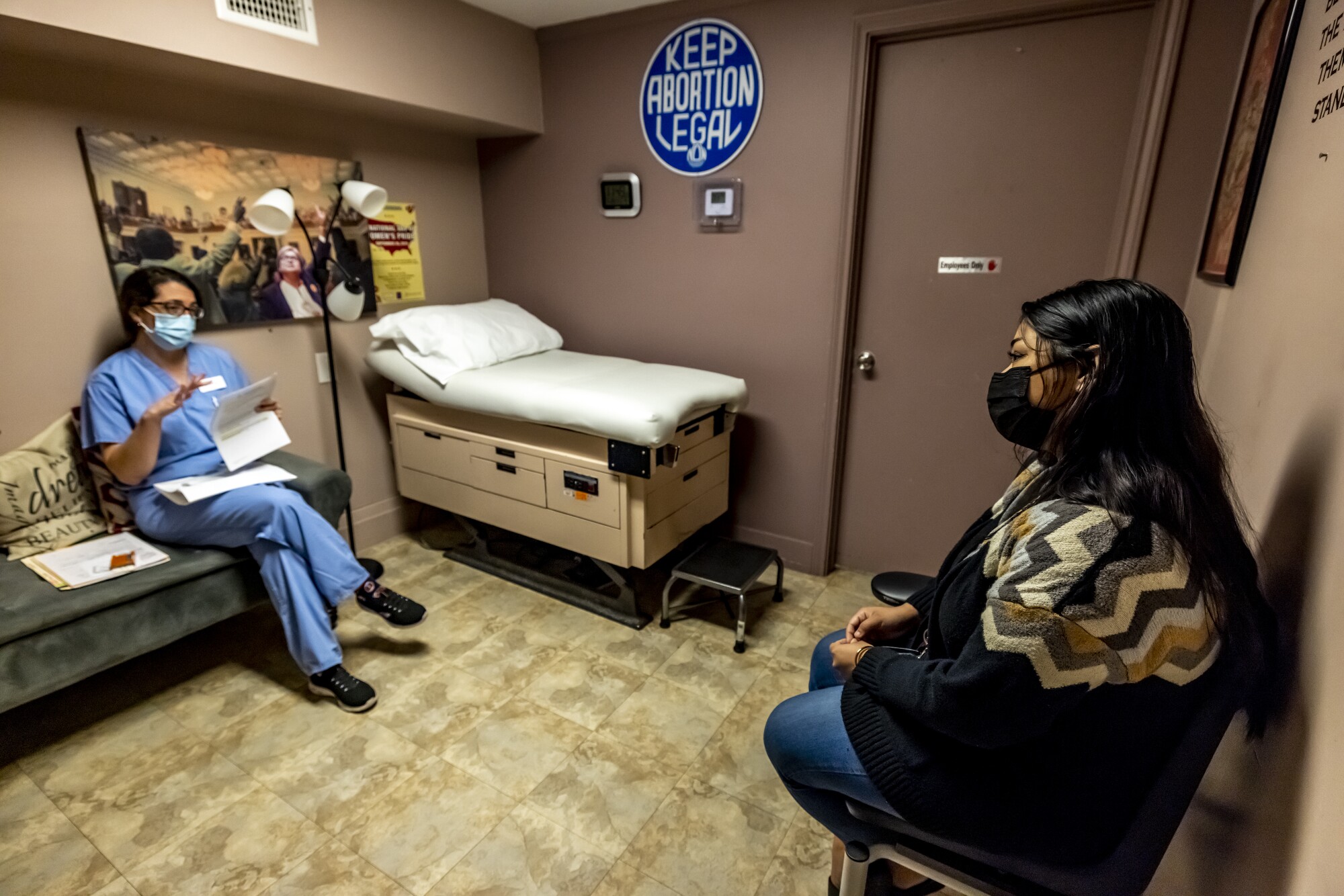 A female doctor, seated left, consults with a woman before she has a medication abortion. 