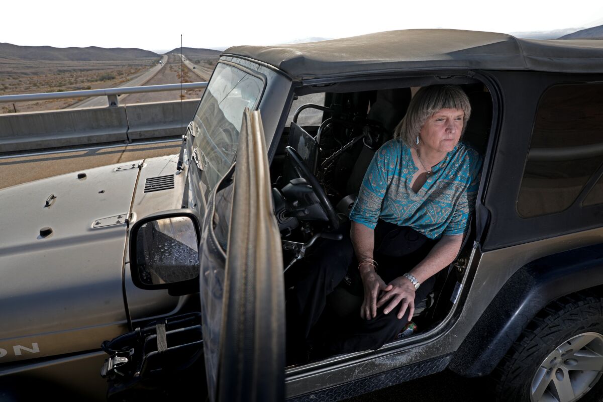 A woman looks out from her Jeep parked on a freeway overpass in the desert
