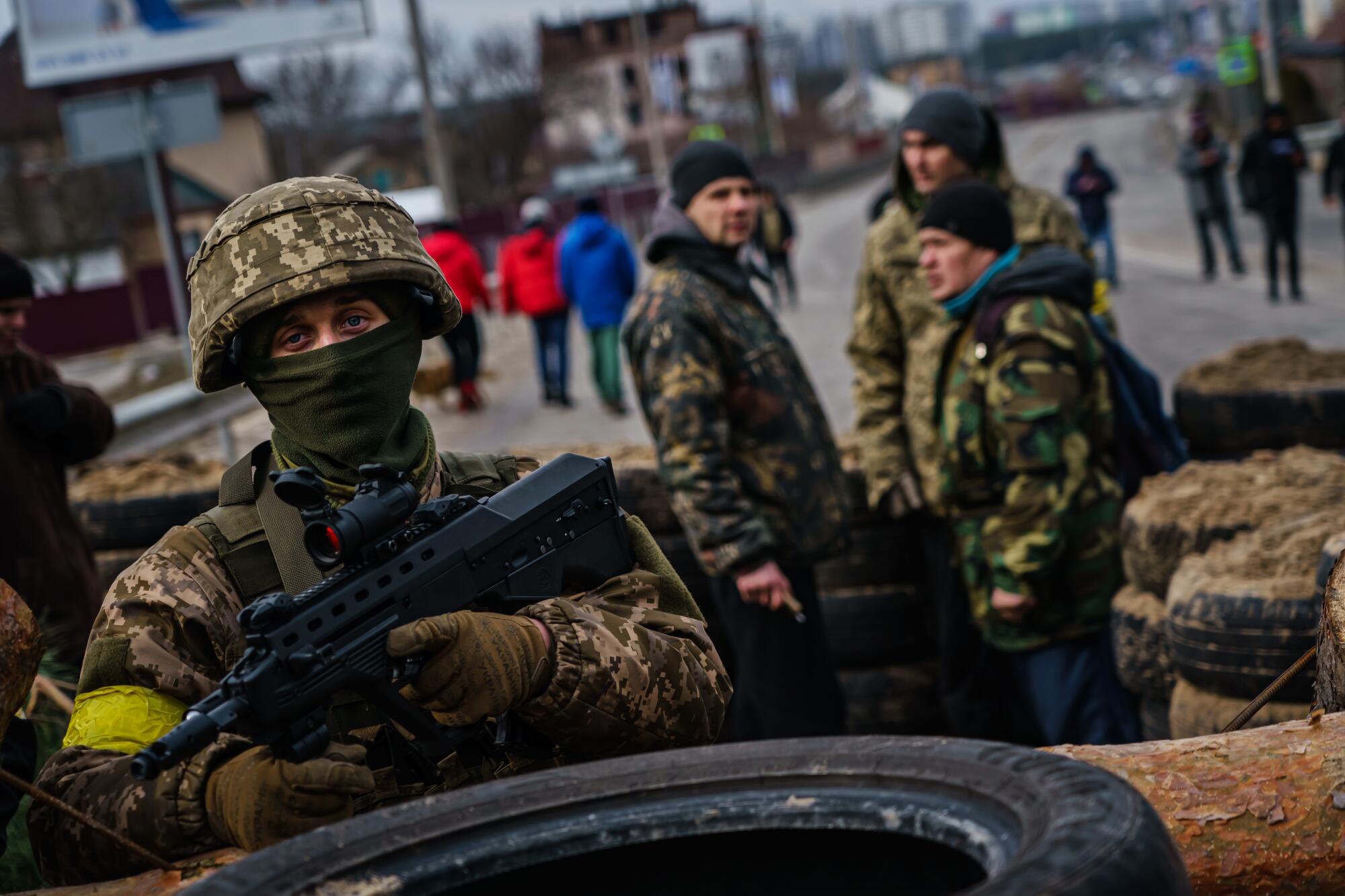 A Ukrainian soldier stands guard outside a checkpoint on the road to Irpin, Ukraine.