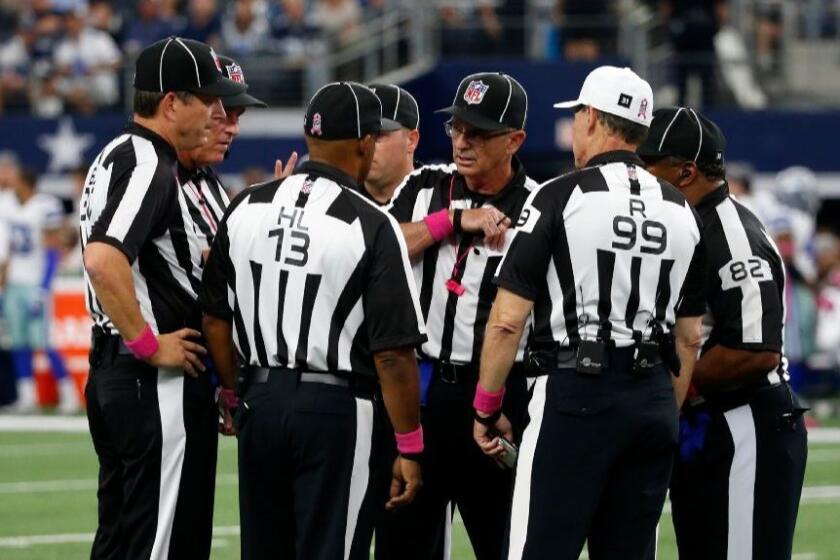 Head linesman Patrick Turner (13), referee Tony Corrente (99), field judge Buddy Horton (82) and other officials gather on the field during a game between the Bengals and the Cowboys on Oct. 9.