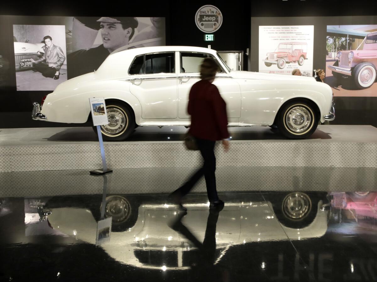 A woman walks past one of Elvis Presley's cars displayed at the "Elvis Presley's Memphis" complex.