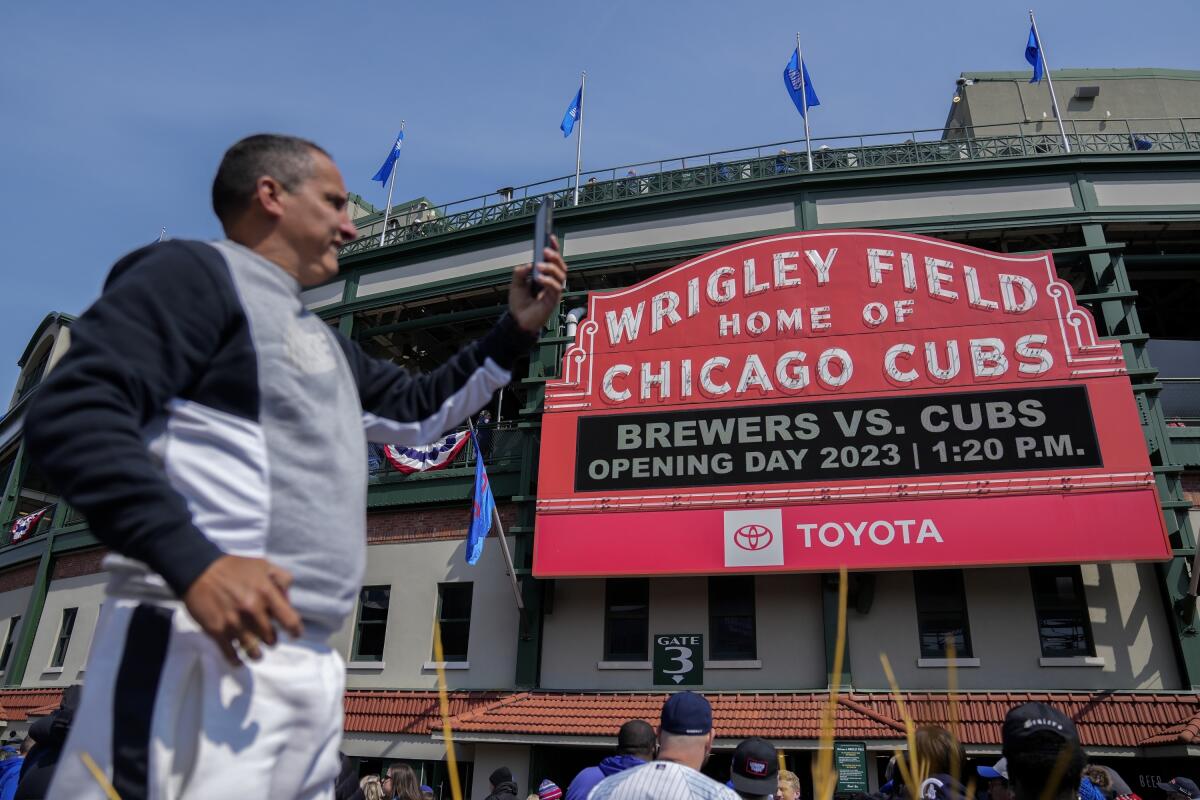 A fan takes a selfie outside Wrigley Field before the 2023 opening day baseball game 