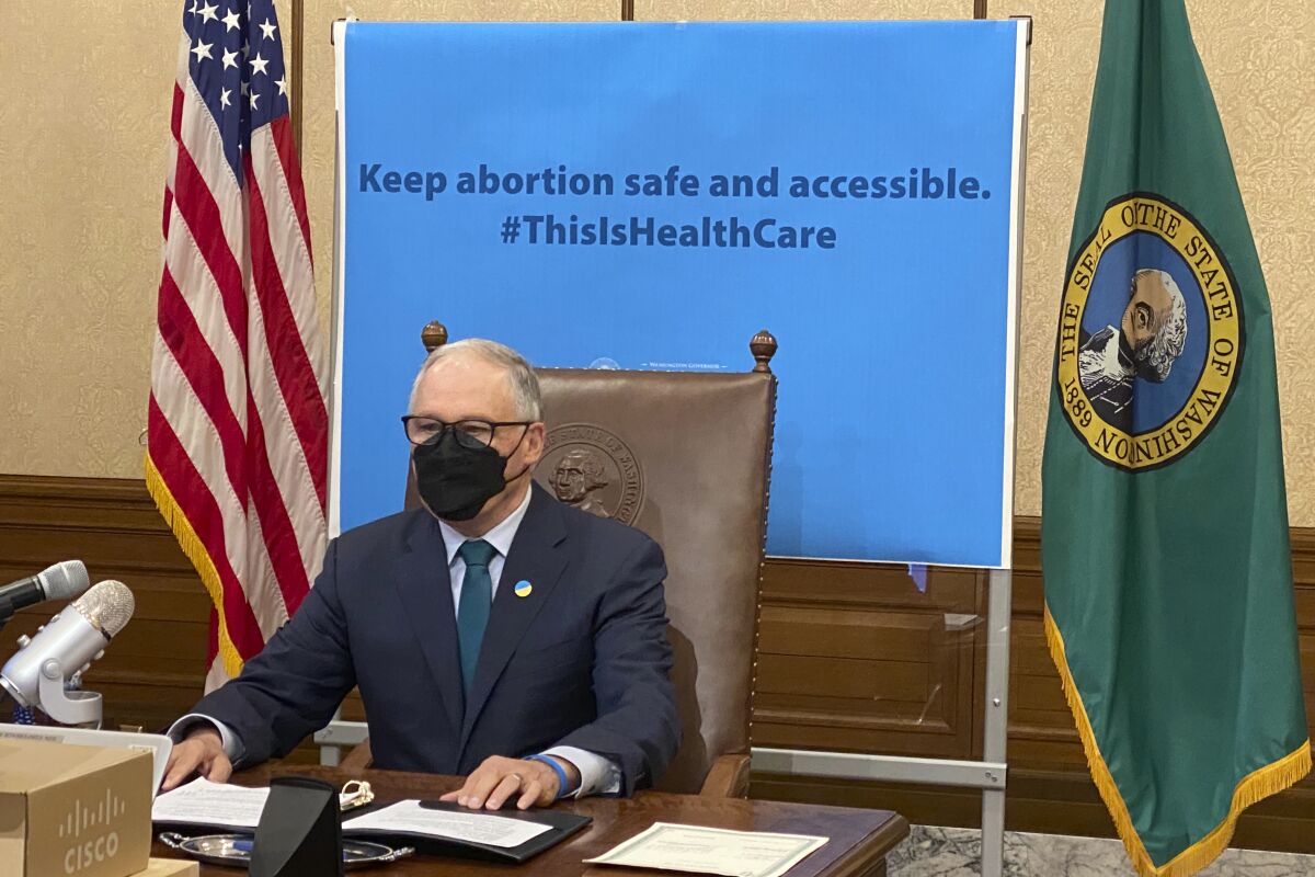 Washington Gov. Jay Inslee is seen before signing a measure that prohibits legal action against both people seeking an abortion and those who aid them, on Thursday, March 17, 2022, in Olympia, Wash. Inslee's signature comes days after the Legislature in neighboring Idaho approved a bill modeled on a law in Texas that allows lawsuits to enforce a ban on abortions performed after six weeks of pregnancy. (AP Photo/Rachel La Corte)