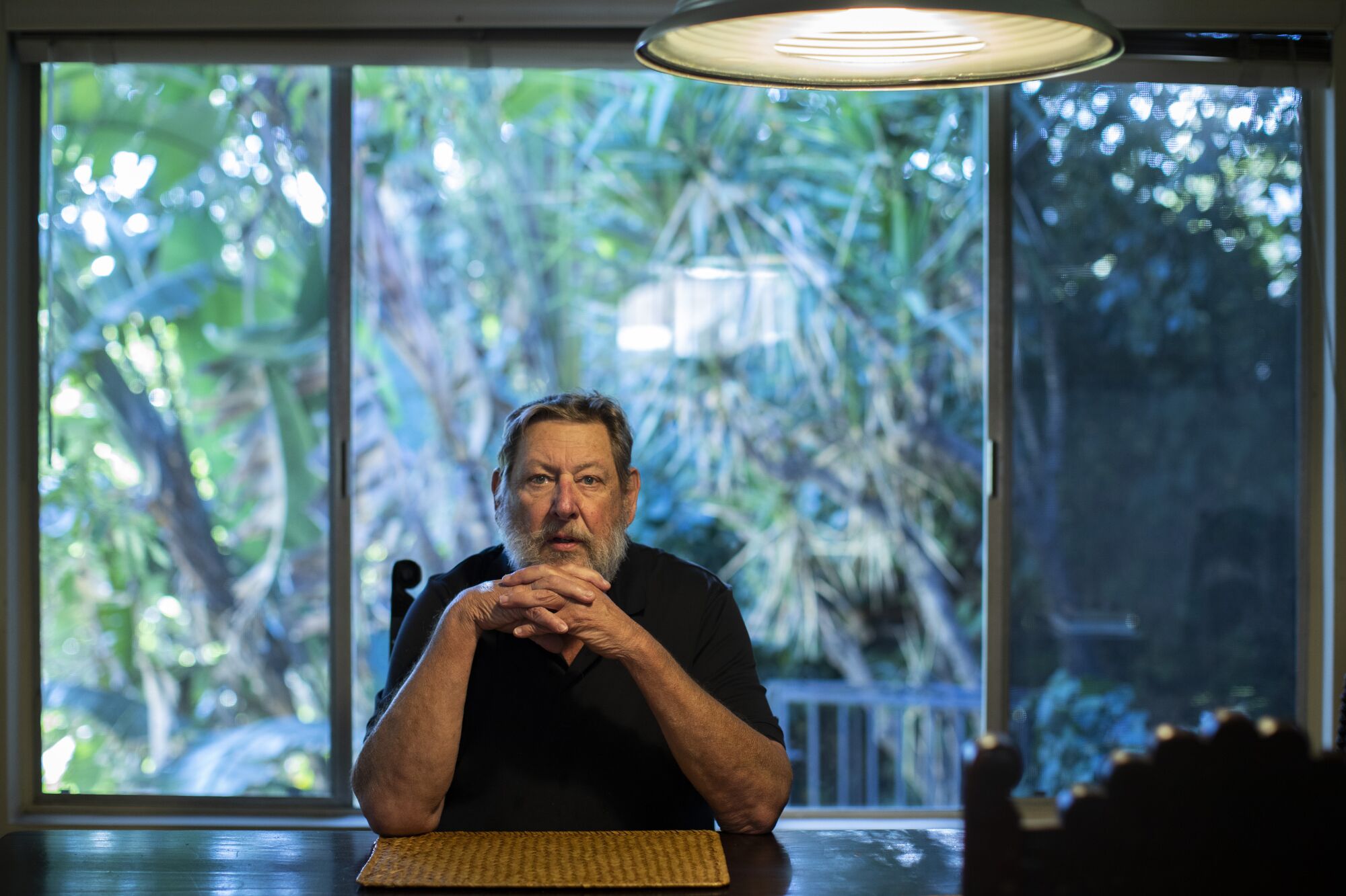 A man sits at a table in front of a window.