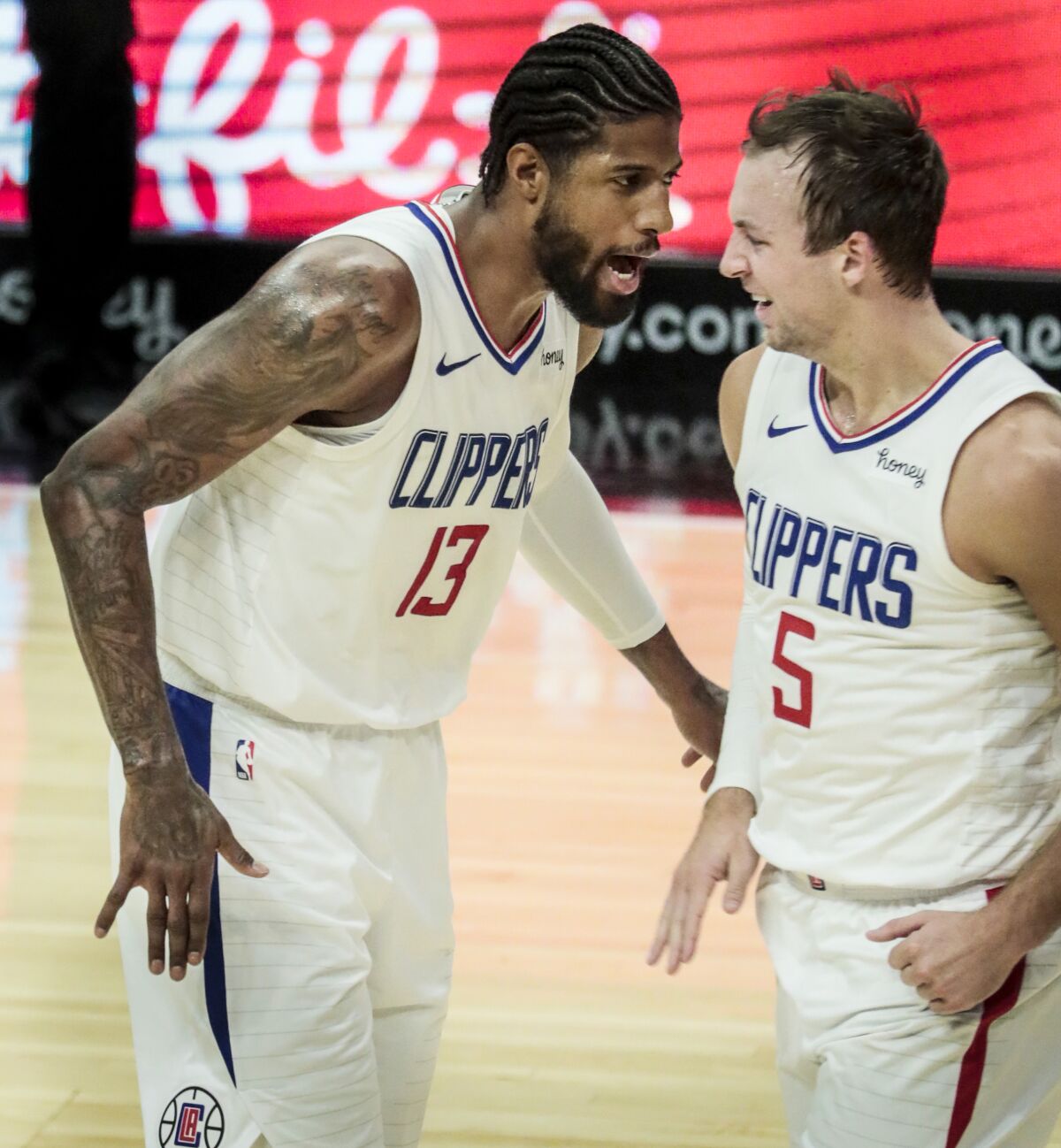 Clippers guard Paul George celebrates with guard Luke Kennard after making a three-point shot.