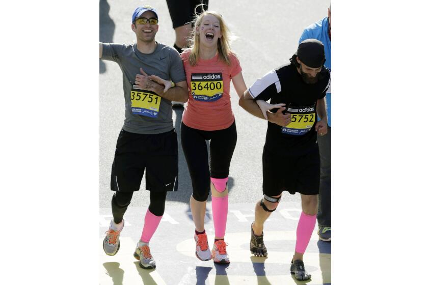 Timothy Haslet, left, and David Haslet celebrate with sister Adrianne Haslet-Davis as she crosses the finish line of the 118th Boston Marathon in April 2014. A year earlier, Adrianne Haslet-Davis, a professional dancer, lost her leg in the Boston Marathon bombing.