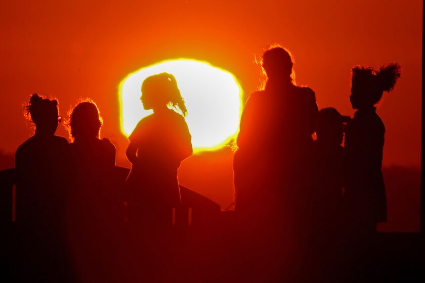 LONG BEACH, CALIF. - SEPT. 1, 2022. The blazing sun silhouettes visitors to Signal Hill after another hot day across Southern California. A brutal heatwave is expected to last through the Labor Day weekend. (Luis Sinco /. Los Angeles Times)