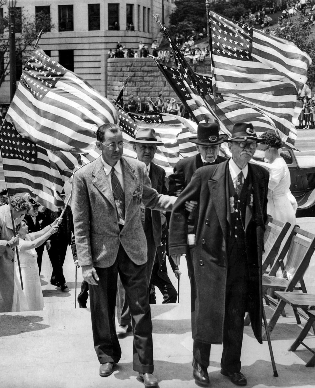 May 30, 1942: Civil War veterans are helped through an arch of flags during a Memorial Day observance at Los Angeles City Hall. The Civil War veterans insisted on walking.