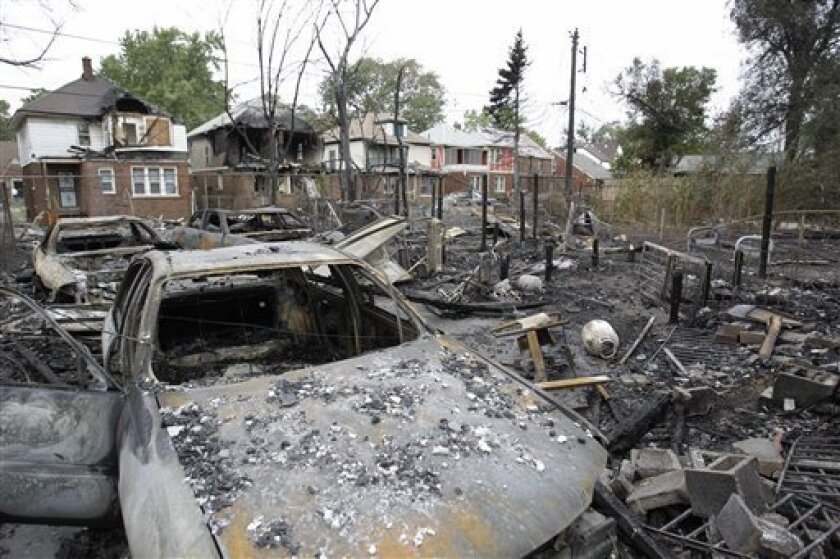 Burned cars and property are seen on the west side of Detroit, Wednesday, Sept. 8, 2010. A wind-swept fire swept through at least three Detroit neighborhoods, destroying dozens of homes, including many that were vacant, officials said. (AP Photo/Carlos Osorio)