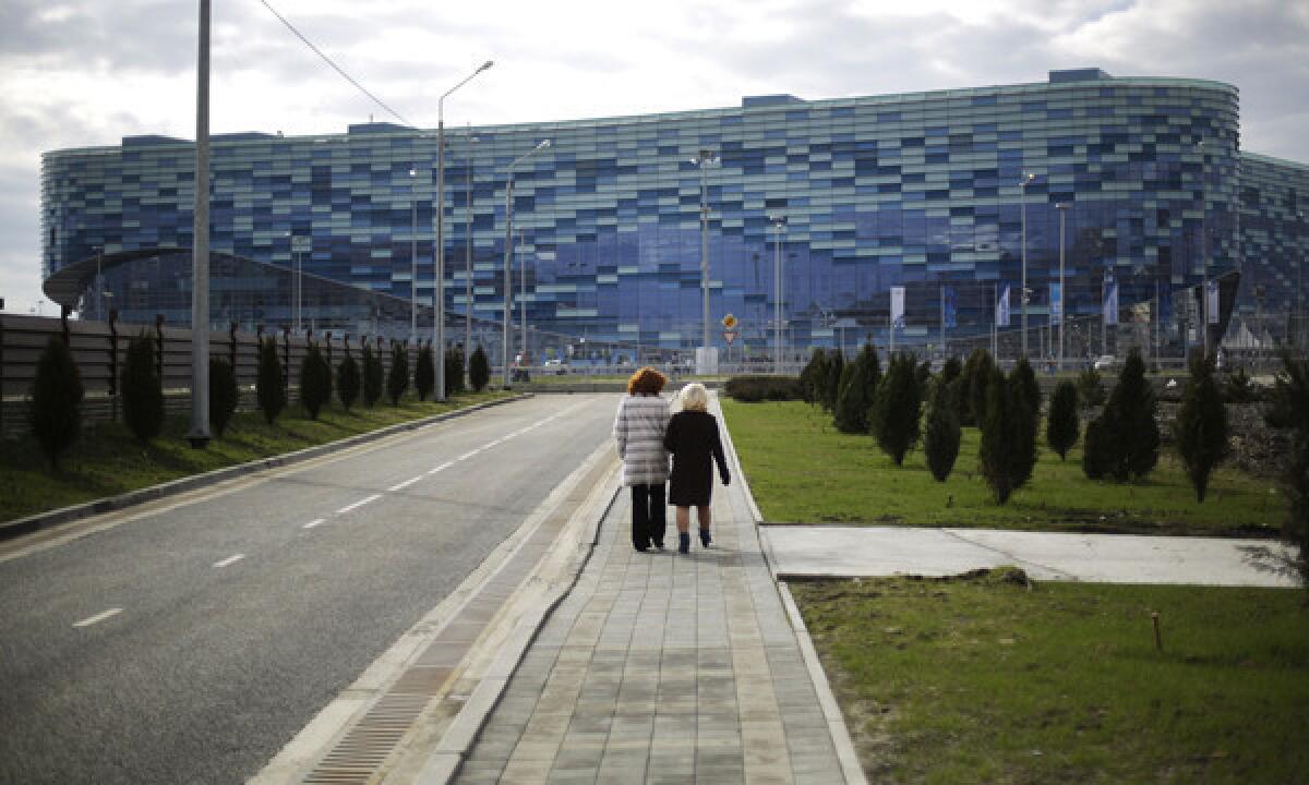 Local residents walk down a street separated by a security perimeter in front of the Iceberg Skating Palace in Sochi, Russia, before the start of the Winter Olympic Games.