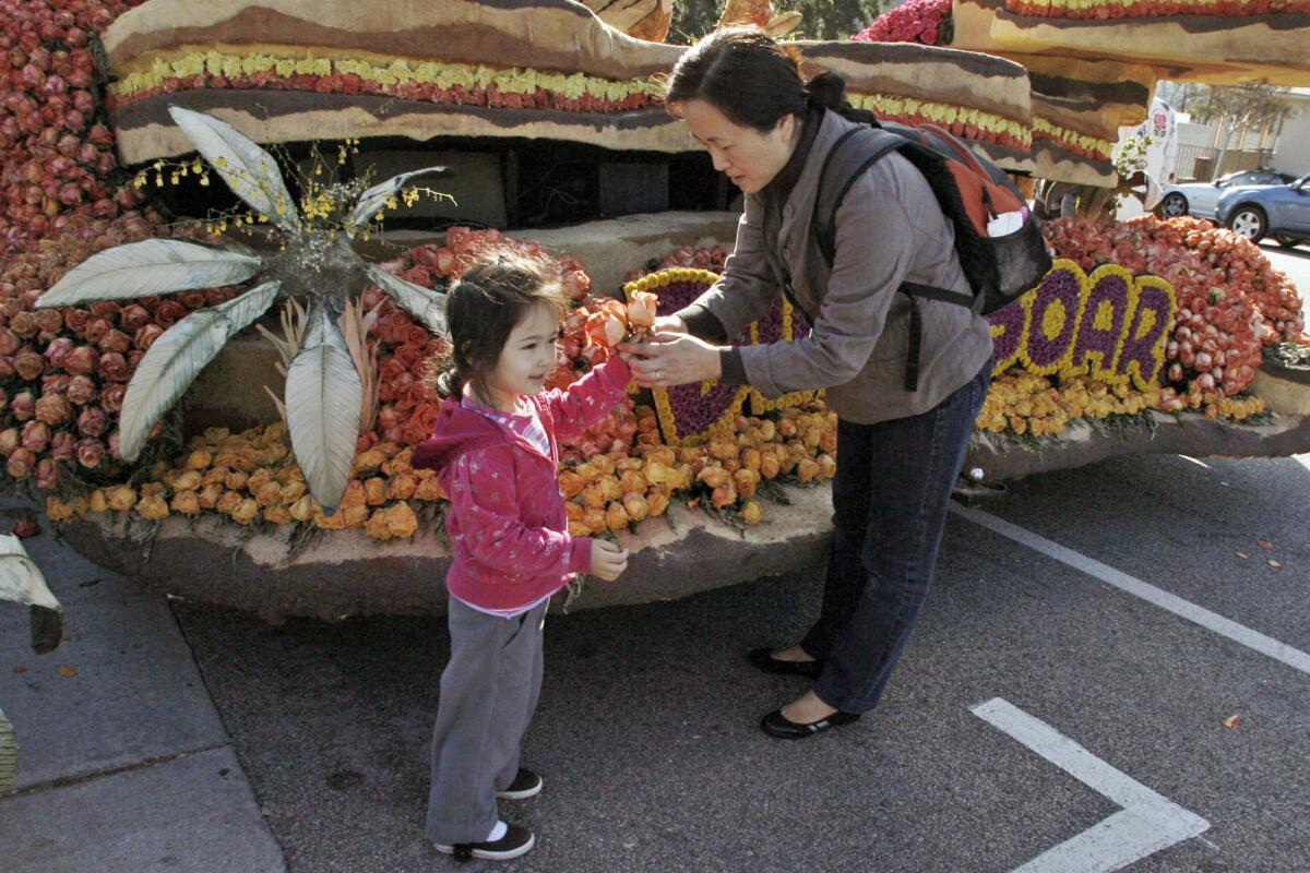Eleni Koutsoukos, 4, receives a flower from her mother, Lin Chen, while visiting the Dino-Soar float at Memorial Park on Saturday.