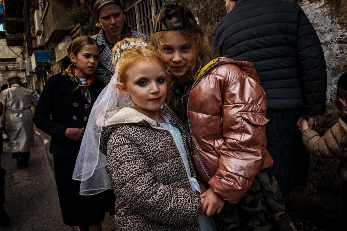 6 岁的宝琳娜·霍夫曼 (Paulina Hoffman) 和 7 岁的泰拉·霍夫曼 (Teila Hoffman) 在普珥节庆祝活动中与街上的人群混在一起。
