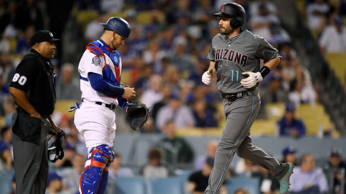 Arizona Diamondbacks' A.J. Pollock, right, scores after hitting a two-run home run as Los Angeles Dodgers catcher Yasmani Grandal, center, and home plate umpire Adrian Johnson stand at the plate during the fifth inning.