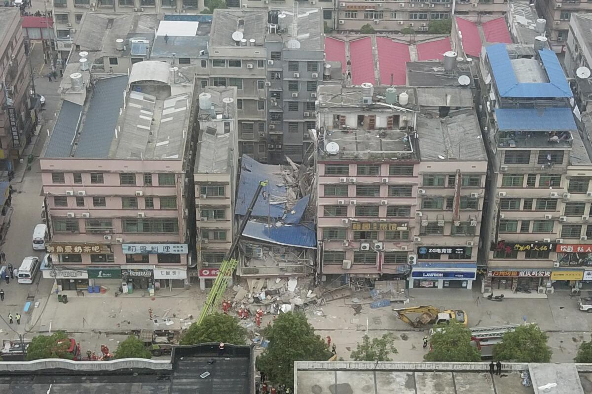 A crane sits in front of a collapsed building.