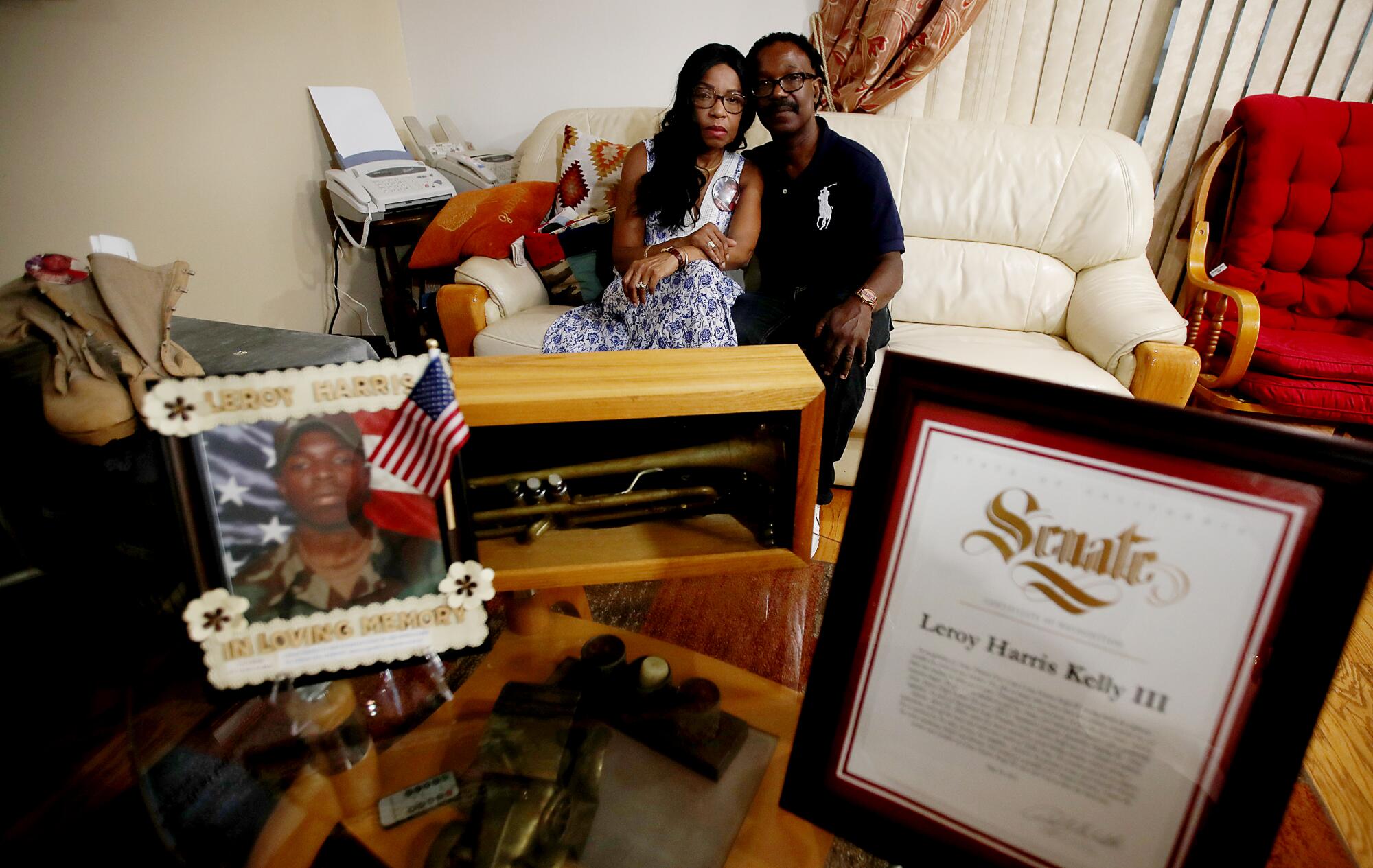 Guiselle and Leroy Harris Jr. sit with mementos of their son, including his combat boots, citations and pictures.