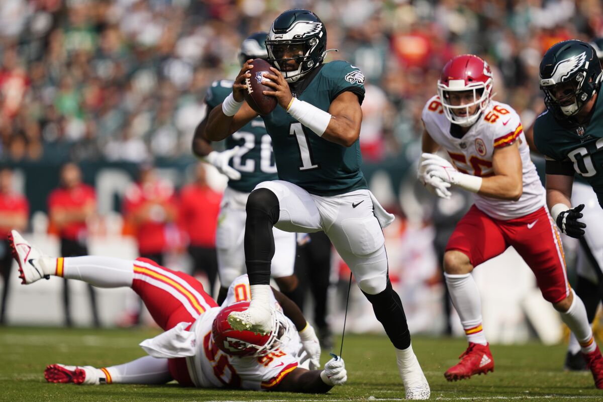 Philadelphia Eagles quarterback Jalen Hurts (1) runs with the ball as Kansas City Chiefs defensive tackle Jarran Reed (90) holds on to part of Hurts' uniform during the first half of an NFL football game Sunday, Oct. 3, 2021, in Philadelphia. (AP Photo/Matt Slocum)