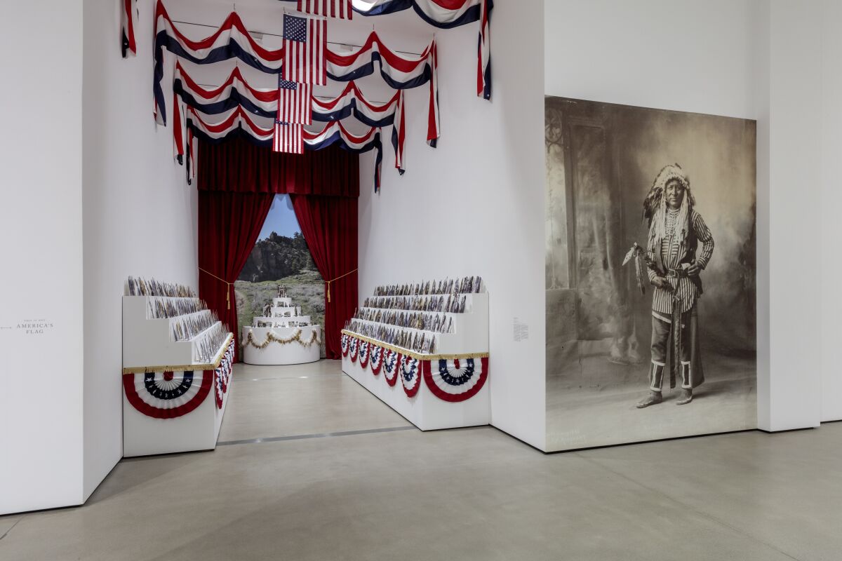 An alcove filled with portrait-cuts and U.S. flag bunting and a large image of a Native American warrior.