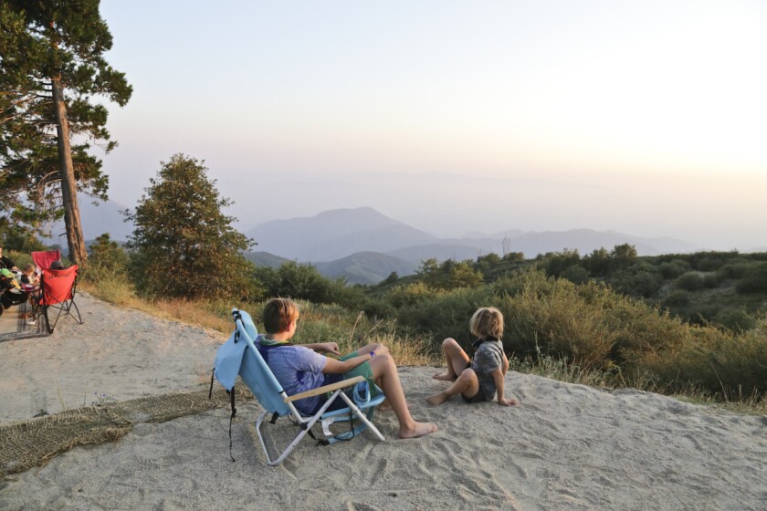 Two kids at a campsite looking at the view of the mountains.