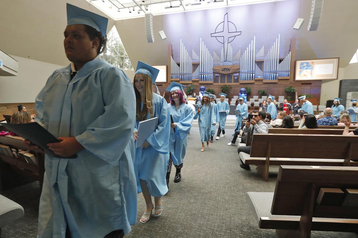 Graduates walk with their diplomas during the Newport-Mesa Cloud Campus commencement ceremony in 2022.