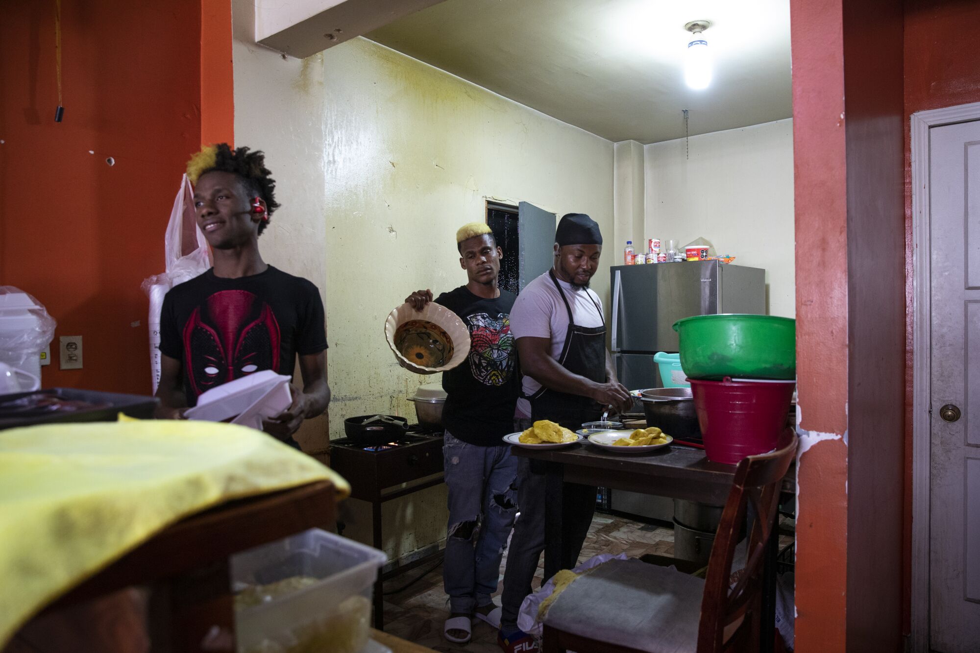 Three people make lunch in a Haitian restaurant in Tijuana.