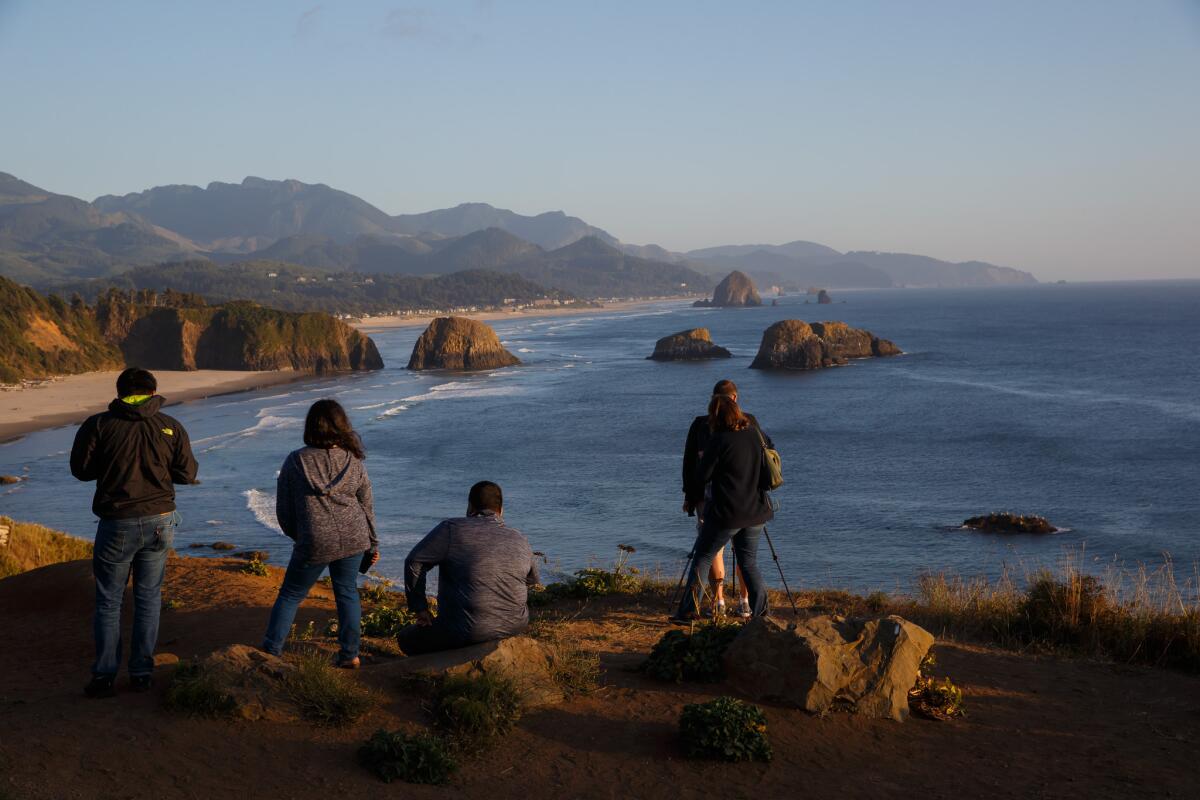 Tourists take in the view from Ecola State Park in Cannon Beach, Ore.