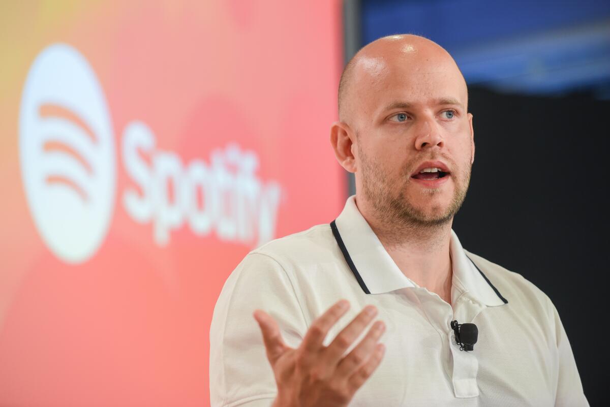 A man speaks standing in front of a Spotify banner.