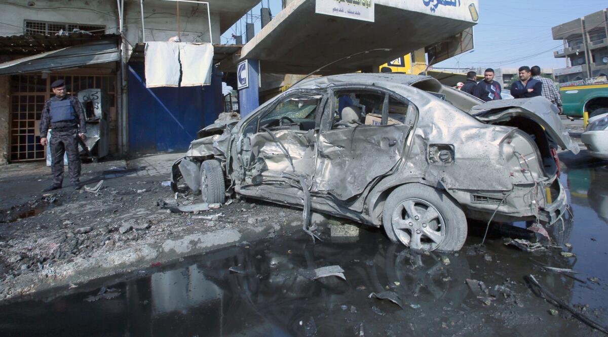 An Iraqi police officer surveys the scene of a car bombing Wednesday in central Baghdad.