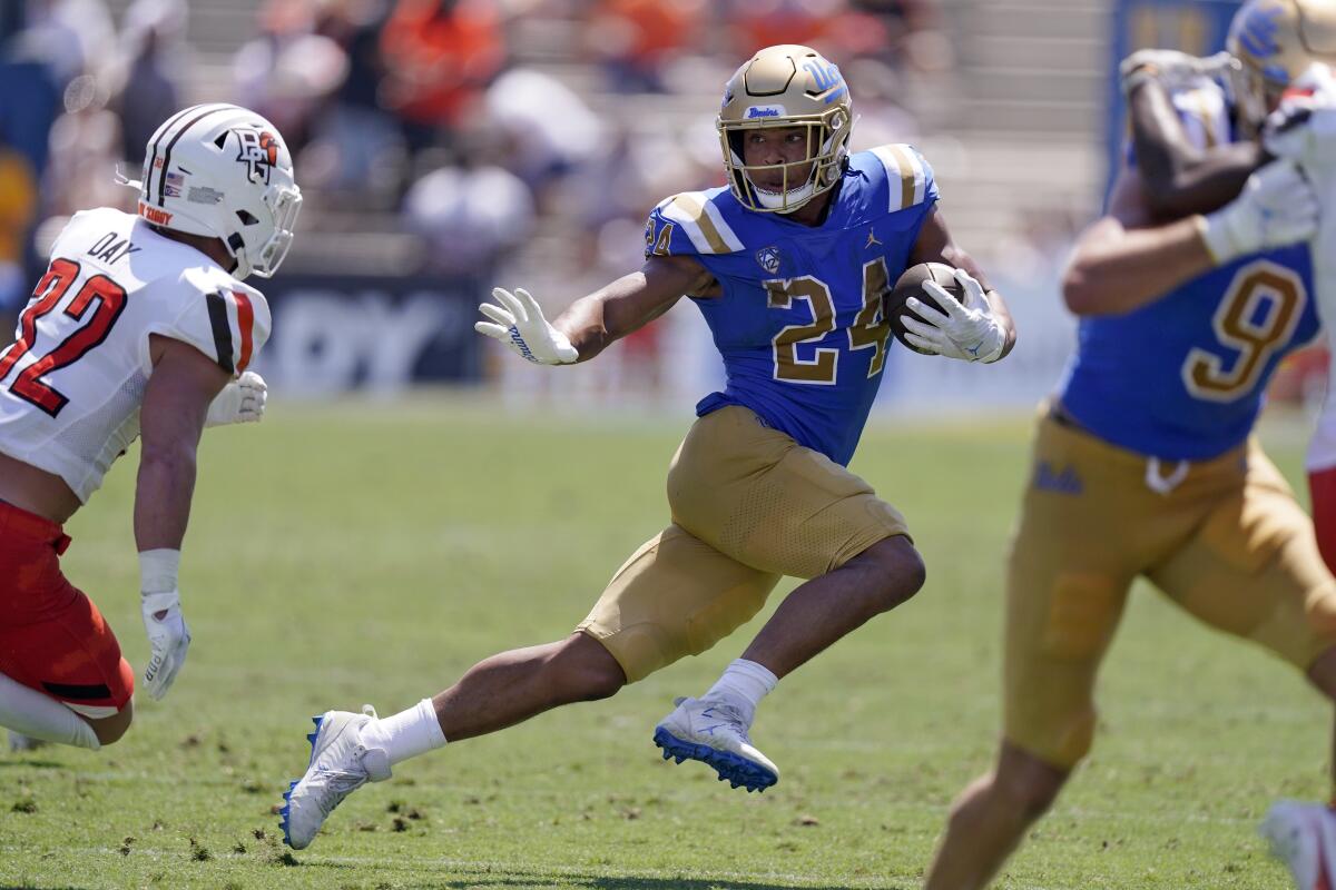 UCLA running back Zach Charbonnet tries to avoid a tackle by Bowling Green safety Patrick Day.