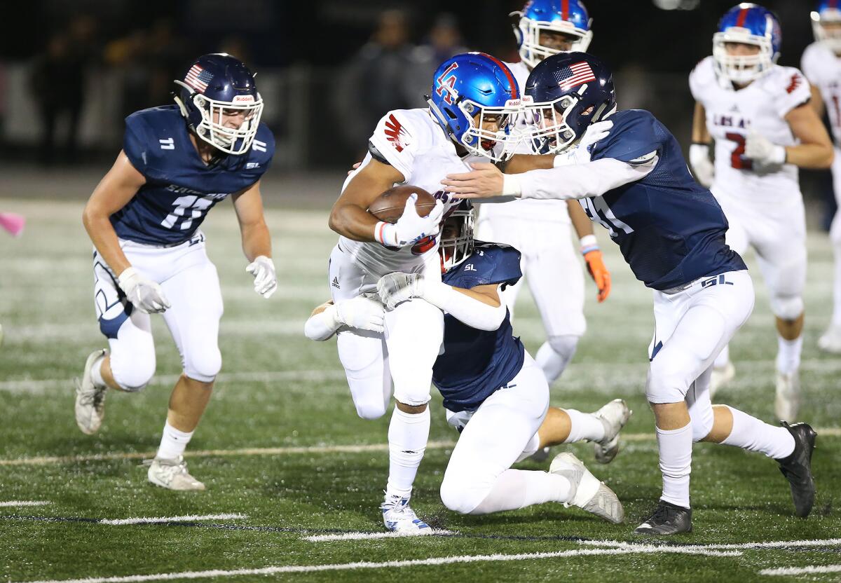 Newport Harbor's Chad Koste, middle, and Zachary Debernarde, right, tackle Los Alamitos running back Josiah Murray in a Sunset League game on Friday at Davidson Field.