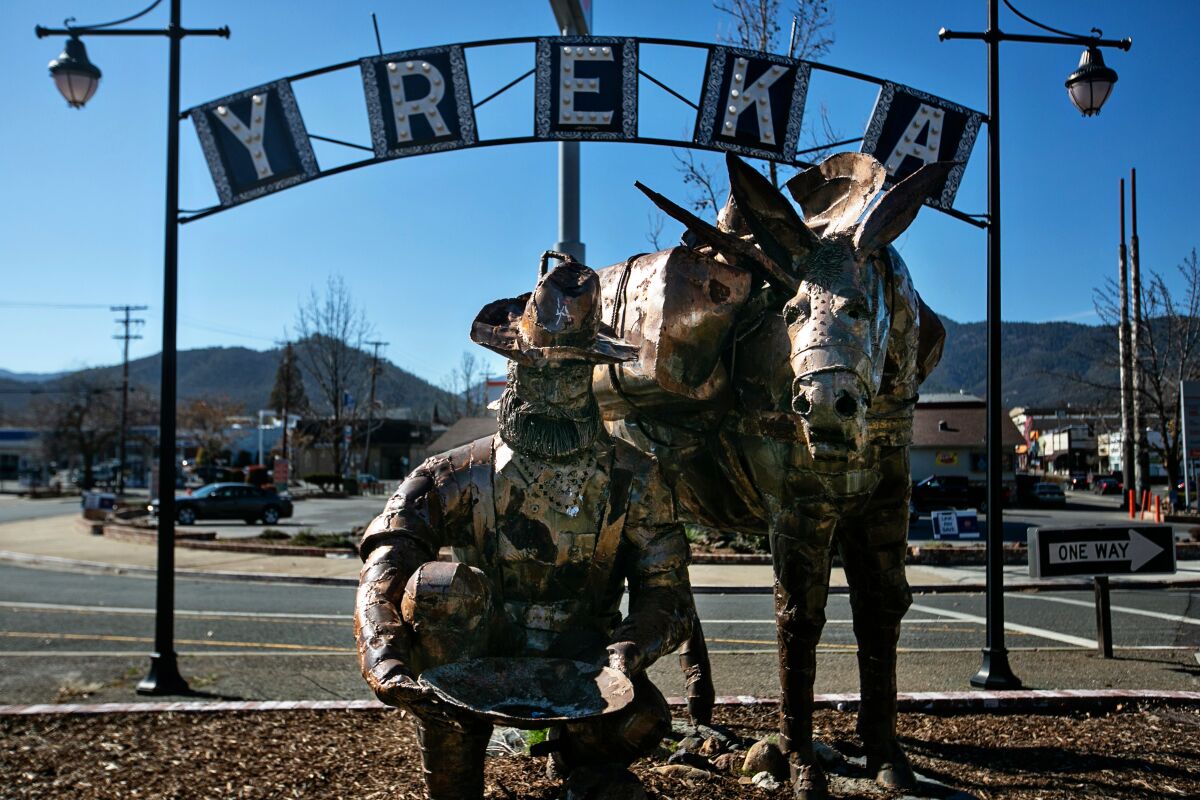 A scrap-metal statue of a prospector panning for gold and a donkey stand beneath a sign that says "Yreka."